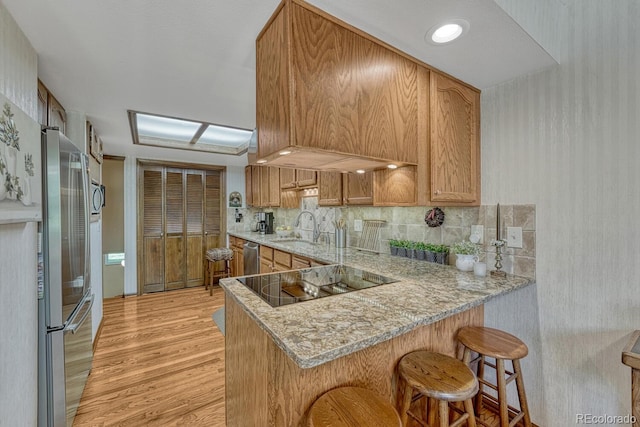 30 Eagle Dr, Littleton, CO 80123 - kitchen featuring appliances with stainless steel finishes, light wood-style floors, a sink, a peninsula, and a kitchen bar