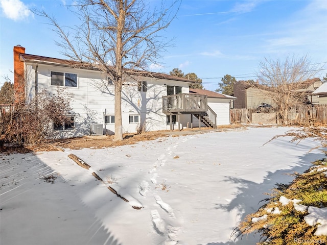 snow covered back of property featuring a wooden deck and central AC unit