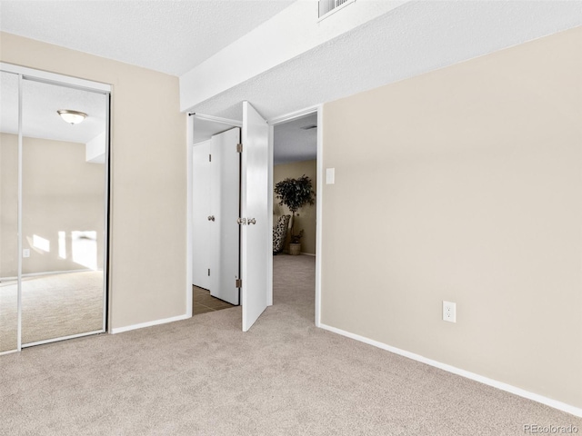 unfurnished bedroom with a textured ceiling, a closet, and light carpet