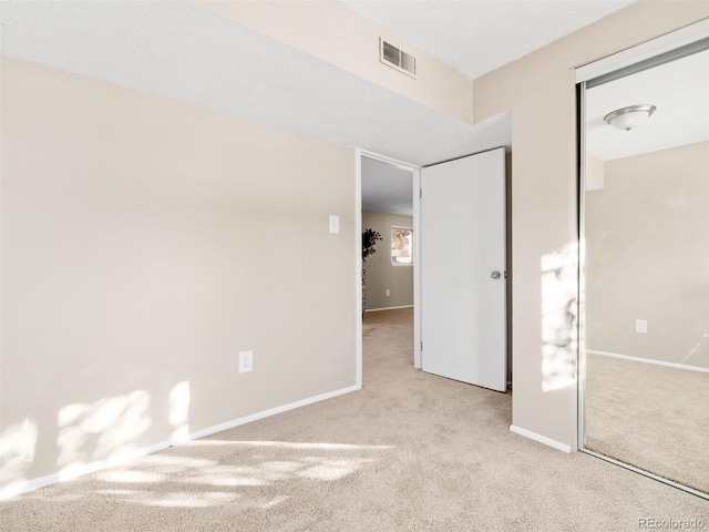 unfurnished bedroom featuring a closet and light colored carpet