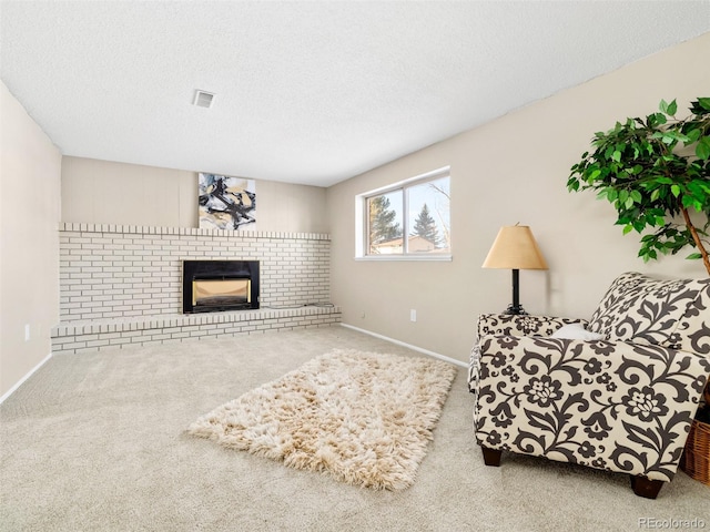 sitting room featuring a brick fireplace, a textured ceiling, and carpet flooring