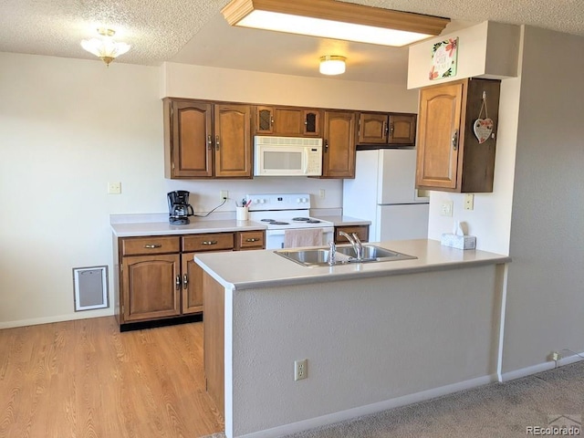 kitchen featuring a textured ceiling, light hardwood / wood-style floors, white appliances, and sink