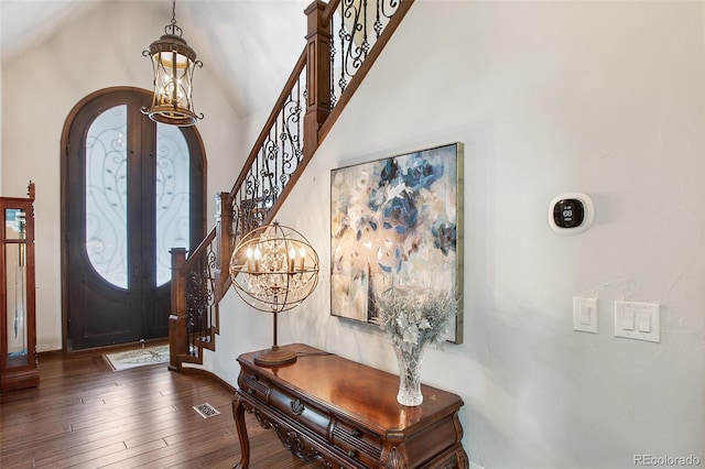 foyer entrance with visible vents, arched walkways, stairs, dark wood-type flooring, and french doors