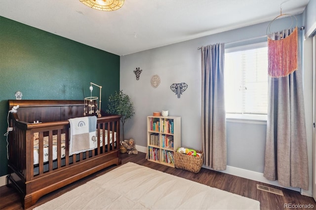 bedroom with hardwood / wood-style floors and a crib