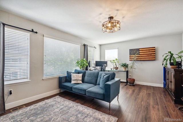 living room with dark wood-type flooring and an inviting chandelier