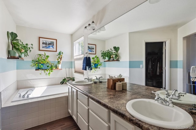 bathroom featuring vanity, tiled tub, and hardwood / wood-style flooring