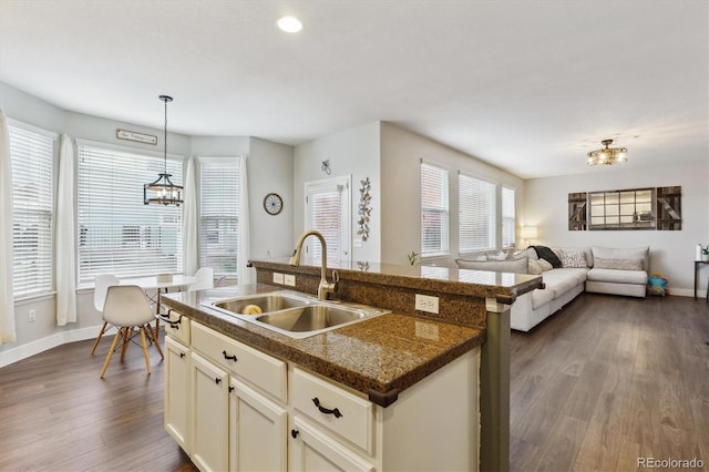 kitchen with sink, an island with sink, decorative light fixtures, and dark hardwood / wood-style flooring