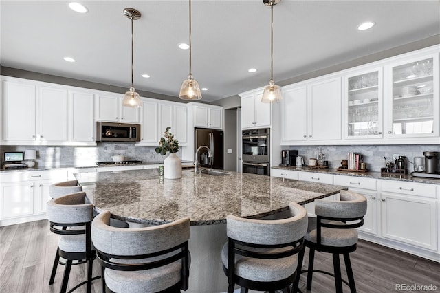 kitchen featuring a kitchen island with sink, appliances with stainless steel finishes, decorative backsplash, and pendant lighting