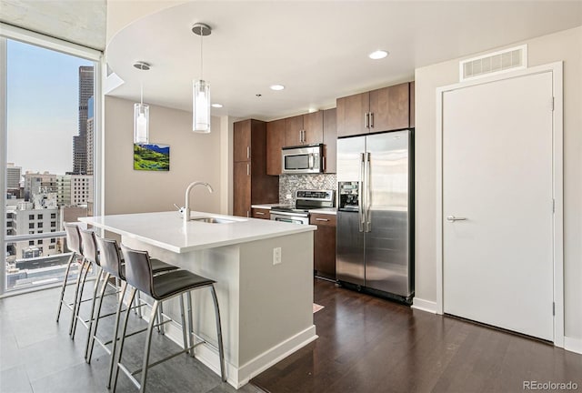 891 14th St Unit 1408, Denver, CO 80202 - kitchen with appliances with stainless steel finishes, decorative backsplash, a breakfast bar area, light countertops, and an island with sink