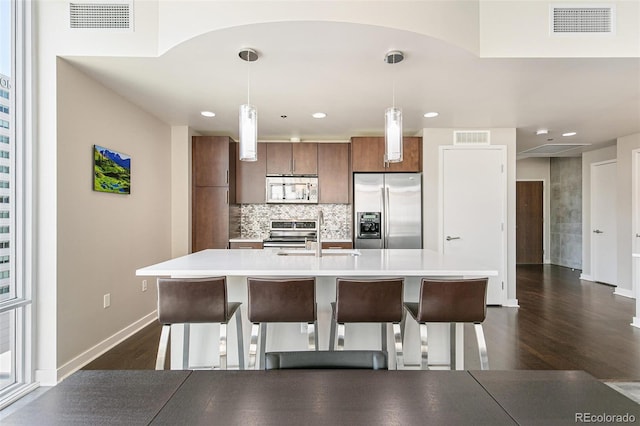 891 14th St Unit 1408, Denver, CO 80202 - kitchen with stainless steel appliances, light countertops, dark wood-style flooring, tasteful backsplash, and decorative light fixtures