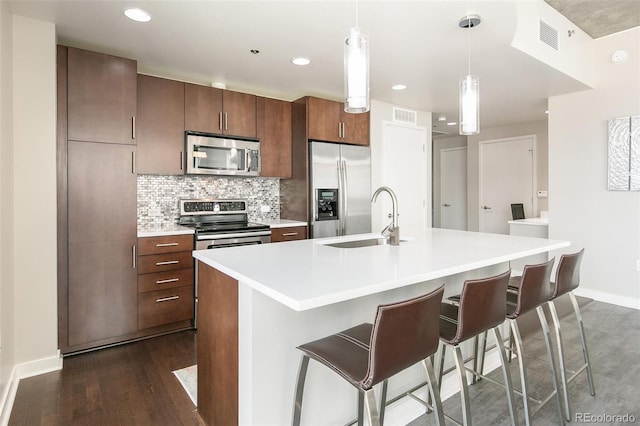 891 14th St Unit 1408, Denver, CO 80202 - kitchen with appliances with stainless steel finishes, light countertops, backsplash, a kitchen island with sink, and a kitchen breakfast bar