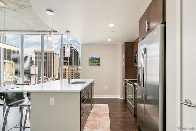 891 14th St Unit 1408, Denver, CO 80202 - kitchen featuring stainless steel appliances, dark wood finished floors, a center island with sink, light countertops, and pendant lighting