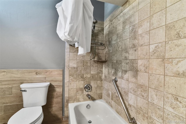 bathroom with tile walls, tiled shower / bath combo, and toilet