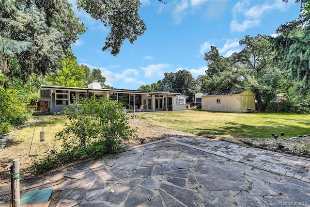 back of house featuring a sunroom, a patio, and a lawn