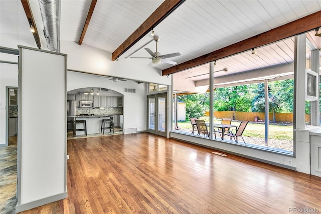 unfurnished living room with plenty of natural light, vaulted ceiling with beams, hardwood / wood-style floors, and ceiling fan