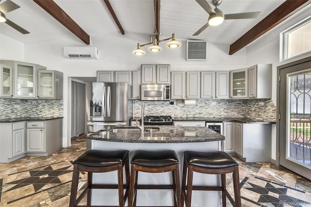 kitchen with stainless steel appliances, dark tile patterned flooring, a center island with sink, and ceiling fan