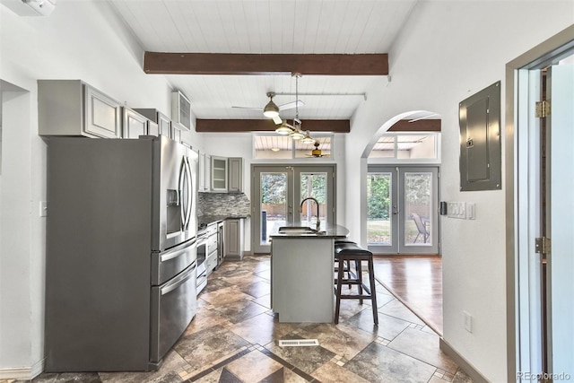 kitchen with backsplash, dark tile patterned floors, stainless steel fridge with ice dispenser, french doors, and a kitchen breakfast bar