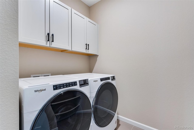 clothes washing area with cabinets and washing machine and clothes dryer