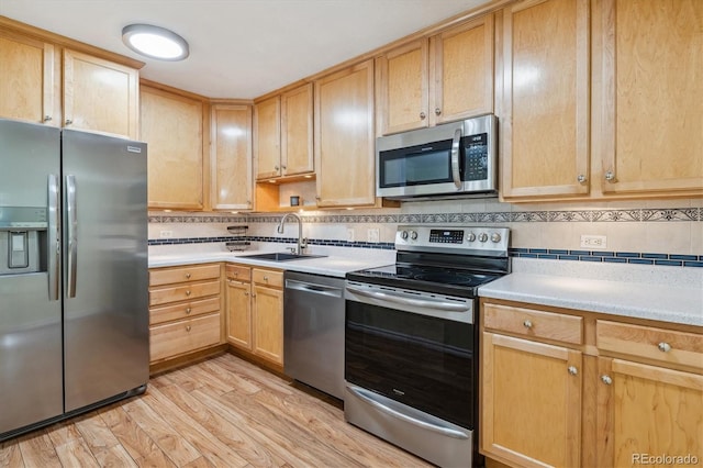 kitchen with decorative backsplash, light hardwood / wood-style floors, sink, and appliances with stainless steel finishes