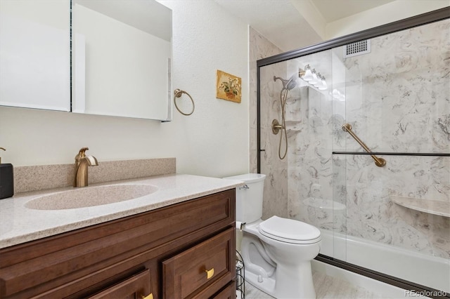 full bath with a marble finish shower, vanity, and toilet