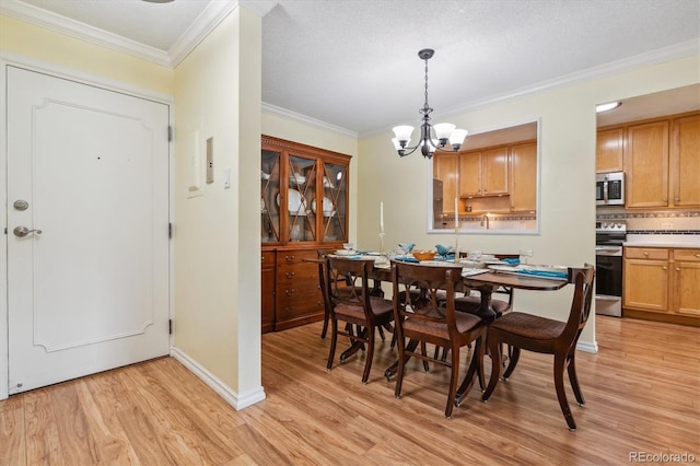 dining room featuring a chandelier, a textured ceiling, light wood-type flooring, and crown molding