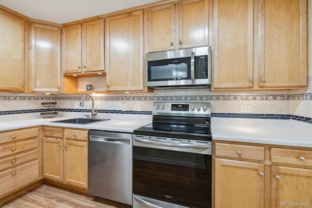 kitchen with decorative backsplash, stainless steel appliances, light hardwood / wood-style flooring, and sink