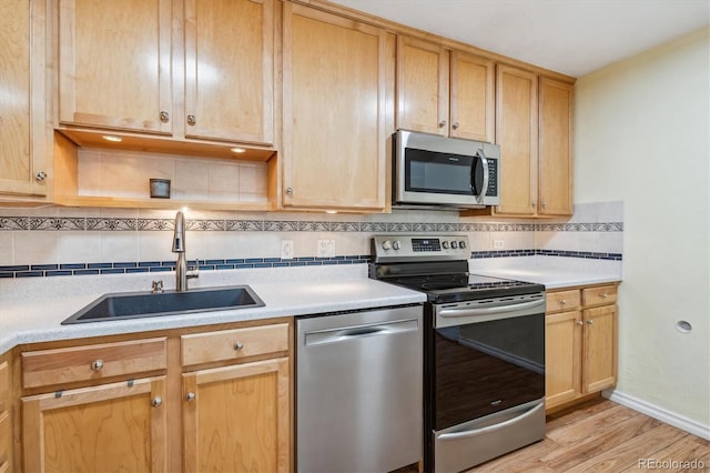 kitchen with tasteful backsplash, sink, stainless steel appliances, and light hardwood / wood-style flooring