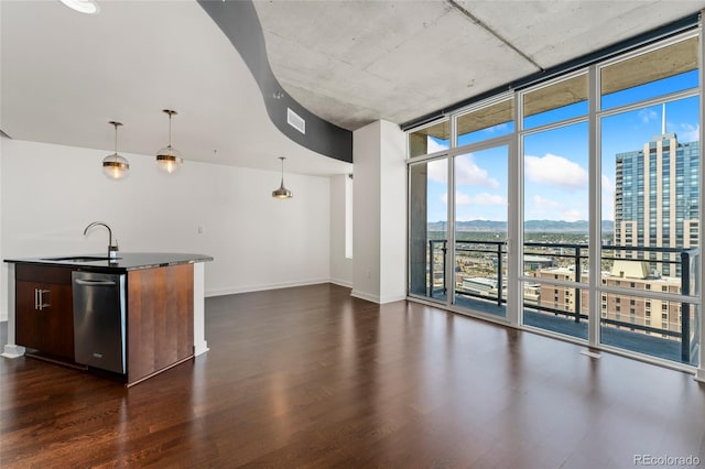 interior space featuring a kitchen island with sink, dark wood-type flooring, sink, hanging light fixtures, and stainless steel dishwasher