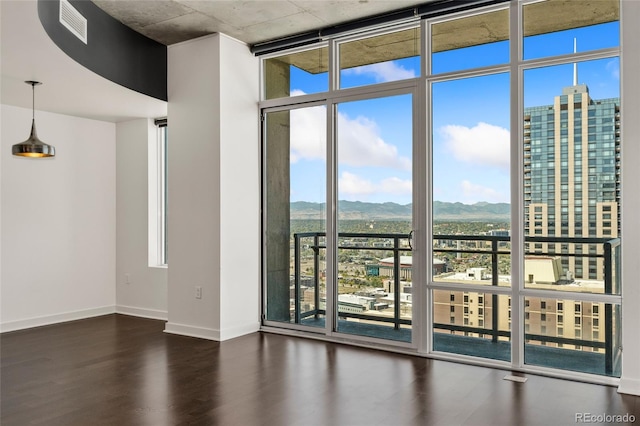 unfurnished room featuring dark wood-type flooring, a mountain view, and expansive windows