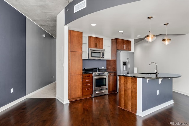 kitchen with hanging light fixtures, an island with sink, a breakfast bar, dark hardwood / wood-style flooring, and stainless steel appliances