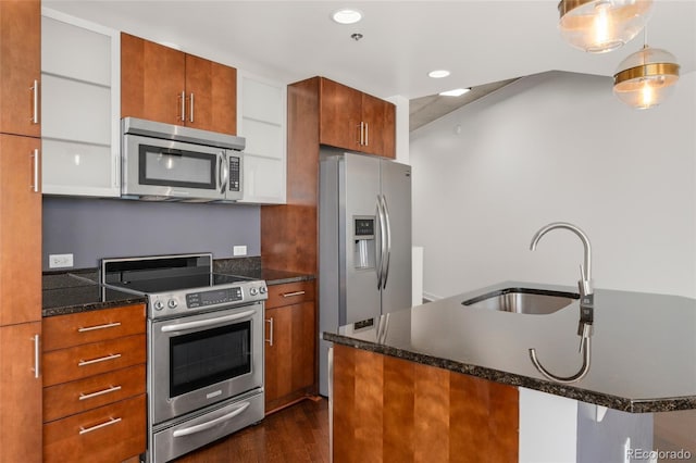 kitchen featuring dark wood-type flooring, appliances with stainless steel finishes, decorative light fixtures, and sink