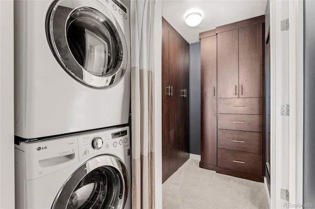 laundry area featuring light carpet and stacked washer / dryer