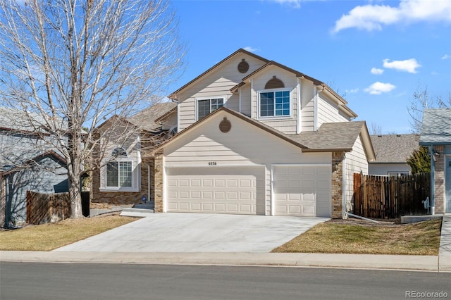 traditional-style house featuring a garage, fence, concrete driveway, and brick siding