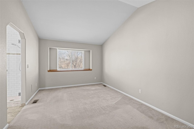 spare room with vaulted ceiling, carpet, visible vents, and baseboards
