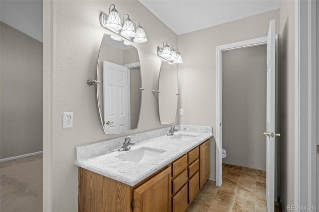 full bath featuring double vanity, a sink, toilet, and stone finish flooring