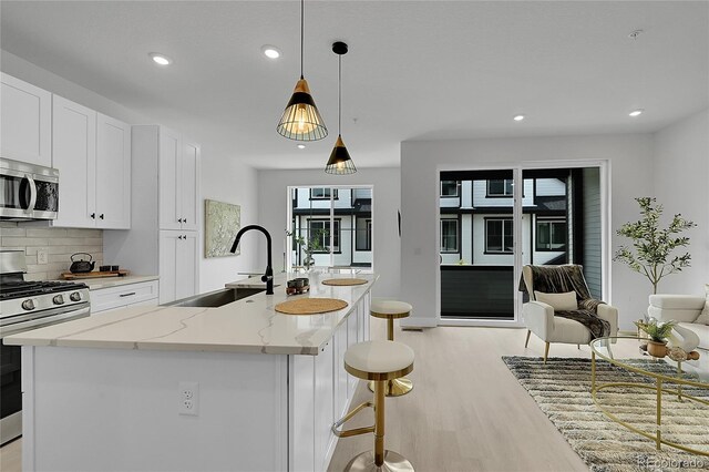 8530 W 52nd Ave Unit A1, Arvada, CO 80002 - kitchen with appliances with stainless steel finishes, a sink, light wood-style flooring, decorative backsplash, and white cabinetry