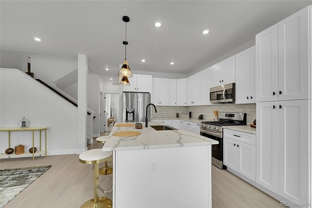 8530 W 52nd Ave Unit A1, Arvada, CO 80002 - kitchen featuring appliances with stainless steel finishes, a sink, light wood-type flooring, decorative backsplash, and recessed lighting