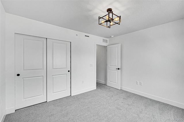 8530 W 52nd Ave Unit A1, Arvada, CO 80002 - unfurnished bedroom featuring a chandelier, carpet, baseboards, a closet, and a textured ceiling