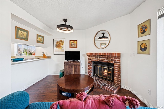 living room with a textured ceiling, a fireplace, wood finished floors, and baseboards