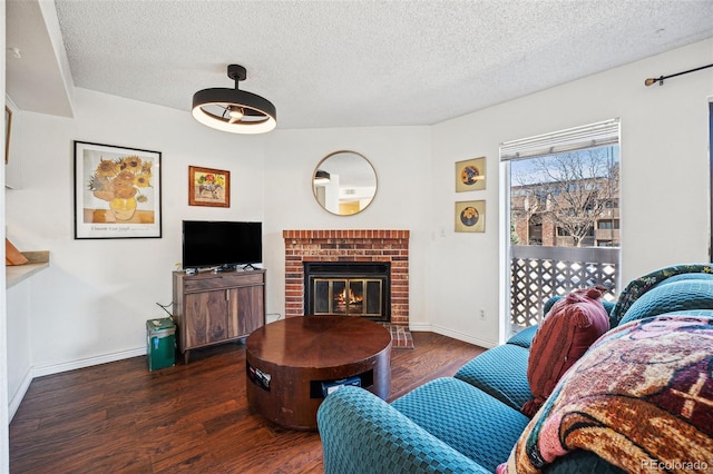 living area with a fireplace, a textured ceiling, baseboards, and wood finished floors