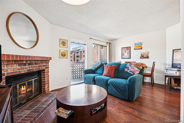 living room featuring a brick fireplace, dark wood finished floors, a textured ceiling, and baseboards