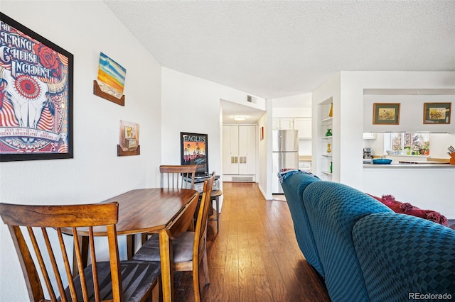 dining space with hardwood / wood-style flooring, visible vents, and a textured ceiling