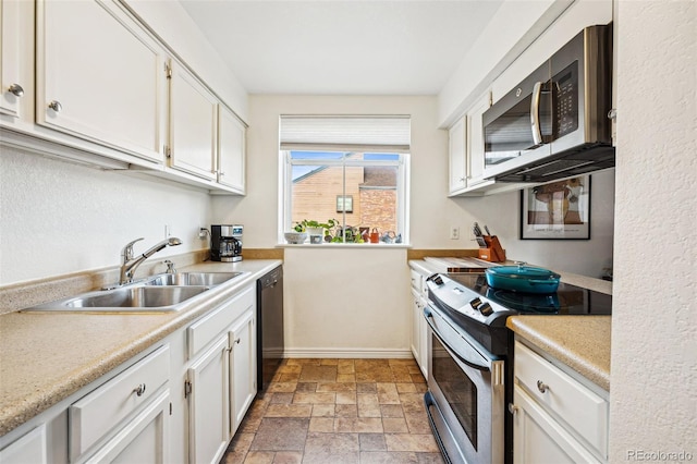 kitchen featuring stone finish floor, appliances with stainless steel finishes, light countertops, and a sink