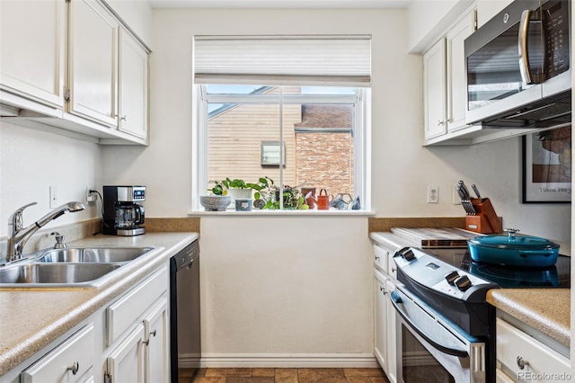 kitchen with baseboards, white cabinets, appliances with stainless steel finishes, light countertops, and a sink