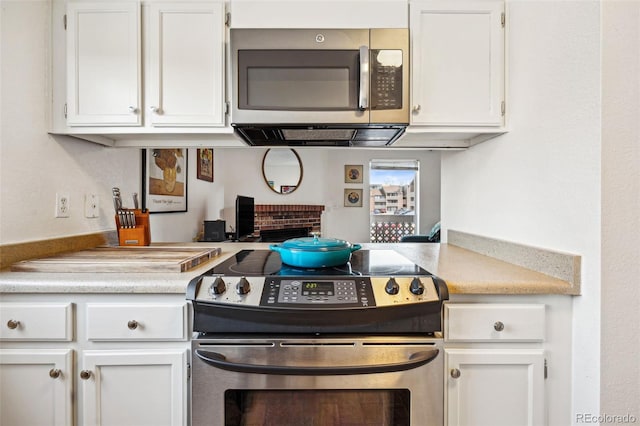 kitchen with stainless steel appliances, light countertops, and white cabinetry