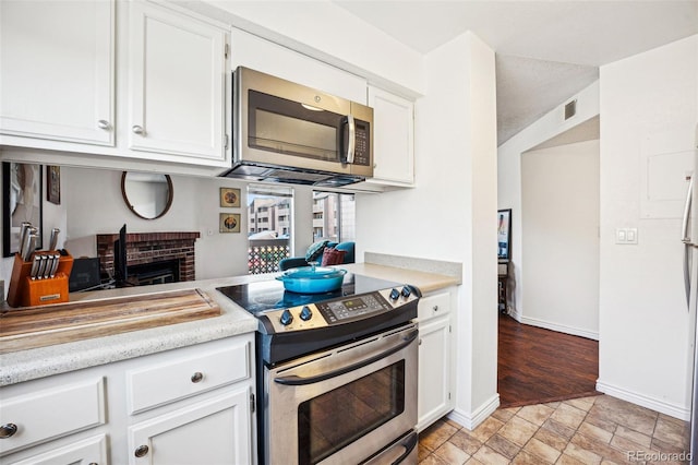 kitchen with white cabinets, baseboards, appliances with stainless steel finishes, and light countertops