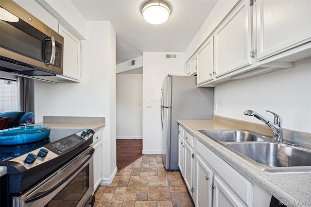 kitchen featuring appliances with stainless steel finishes, light countertops, a sink, and visible vents