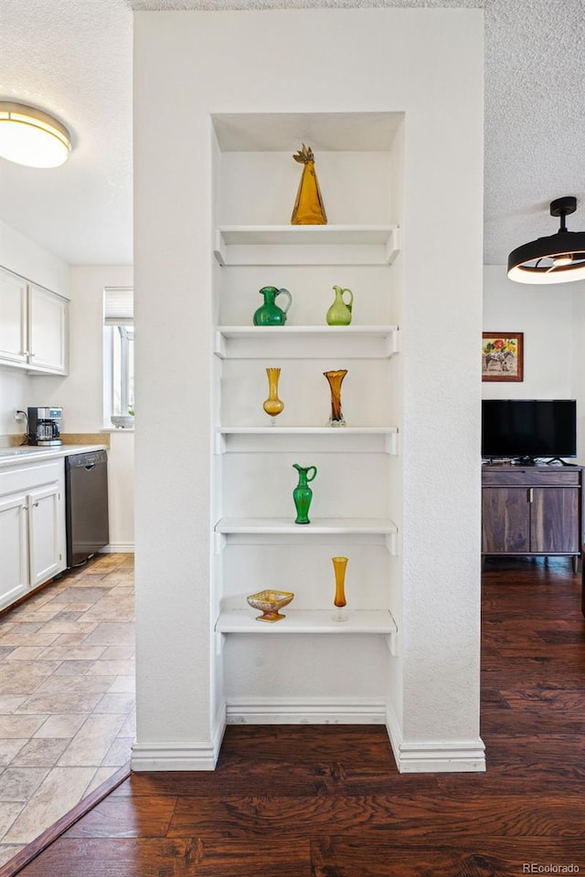 interior details featuring baseboards, a textured ceiling, dishwashing machine, and wood finished floors