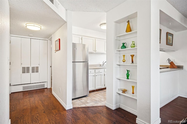 kitchen with freestanding refrigerator, white cabinetry, dark wood finished floors, and a textured ceiling