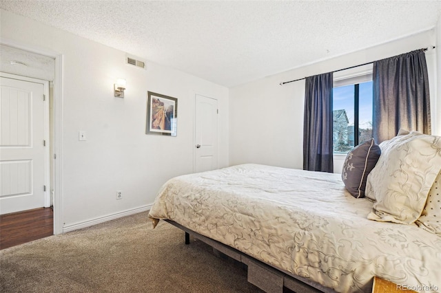 carpeted bedroom with visible vents, a textured ceiling, and baseboards